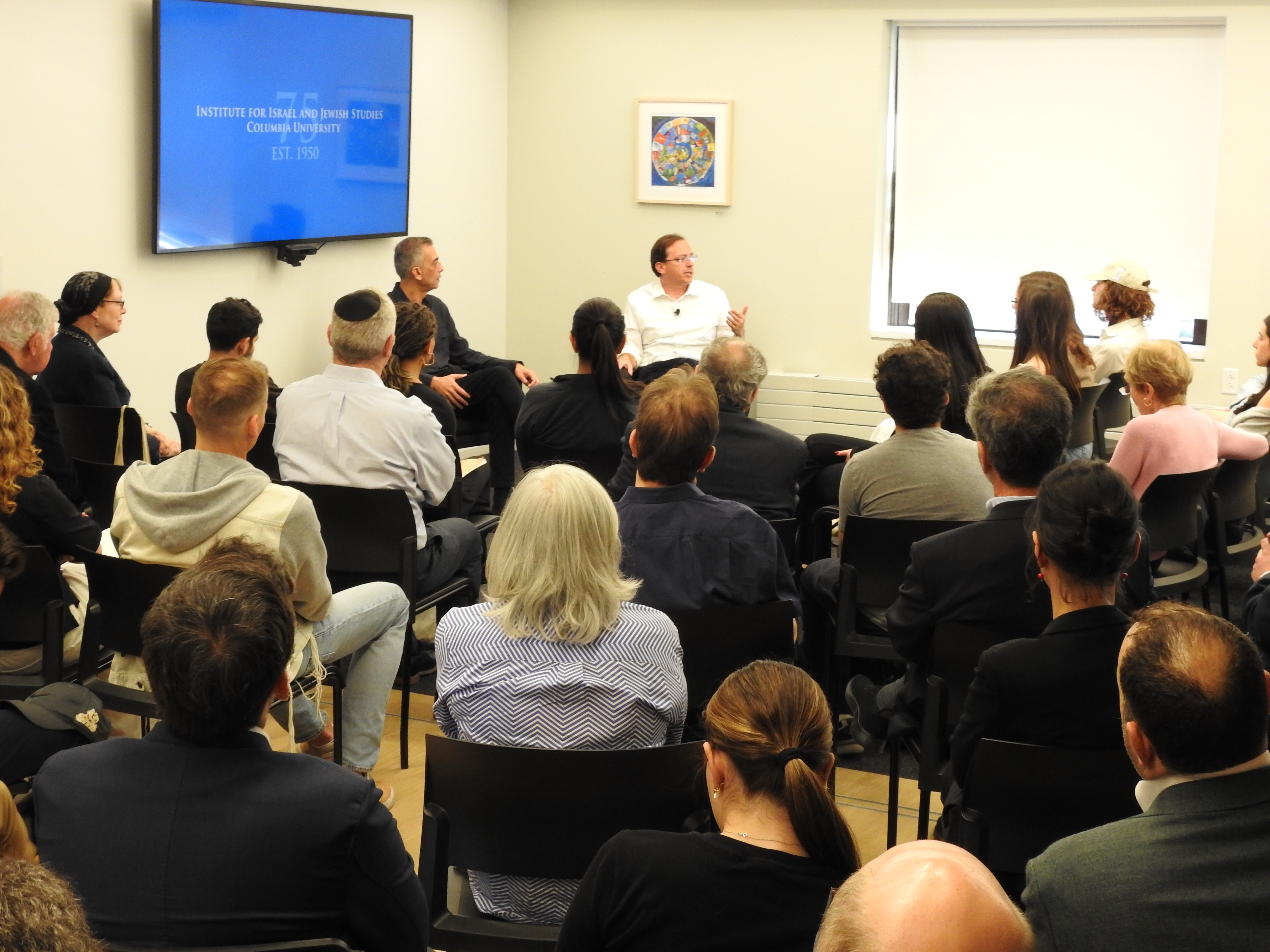 Two men sitting in discussion in front of an audience